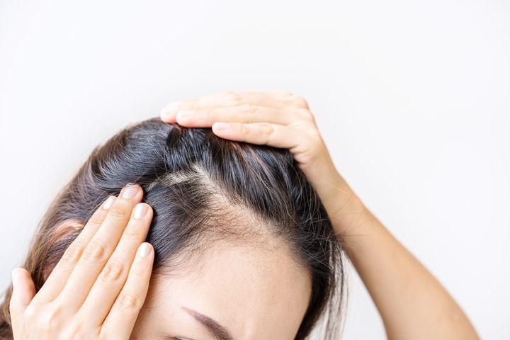 Woman checking a thinning hair parting