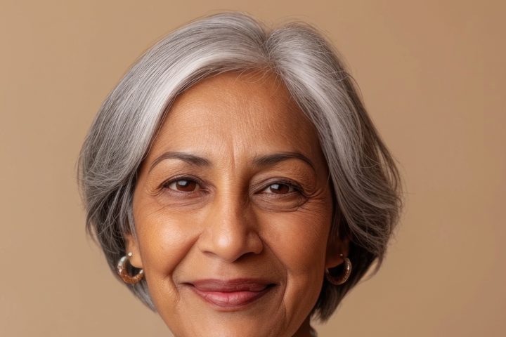 Smiling older woman with grey hair and visible signs of skin ageing